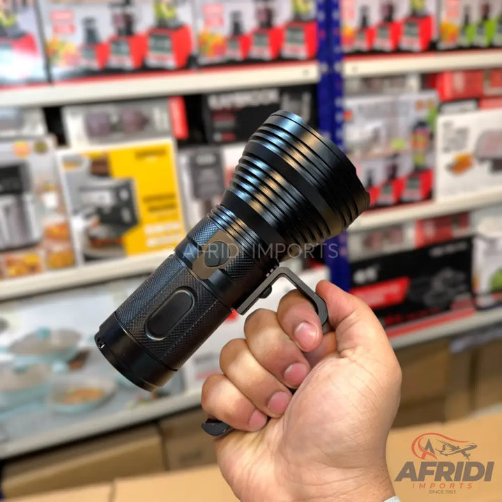 Black handheld flashlight with a side handle.
