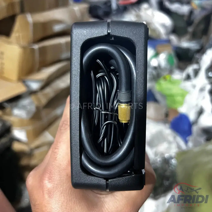 Compact black portable air compressor with an integrated hose and power cable.