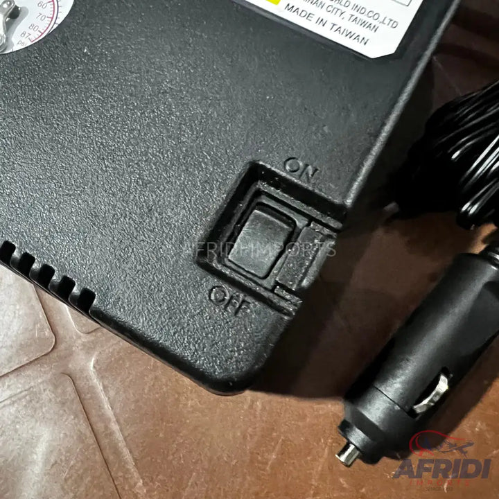 Black air compressor with an on/off switch and a car power adapter.