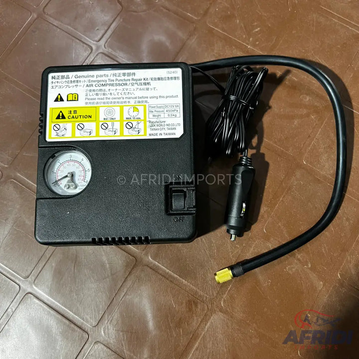 A black portable air compressor with an attached power cord and air hose.