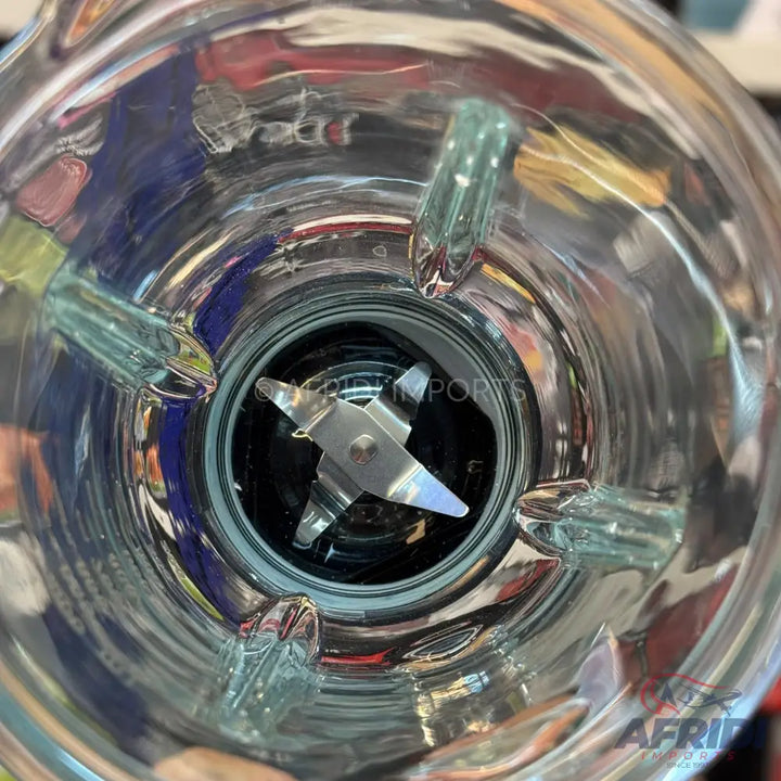 A clear glass blender jar with a four-blade assembly at its base.