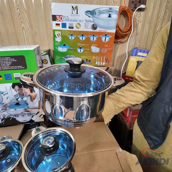 Stainless steel cookware set with blue-tinted glass lids.