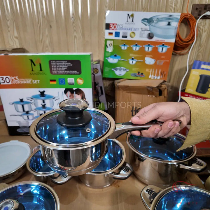 Stainless steel cookware set with blue-tinted glass lids.