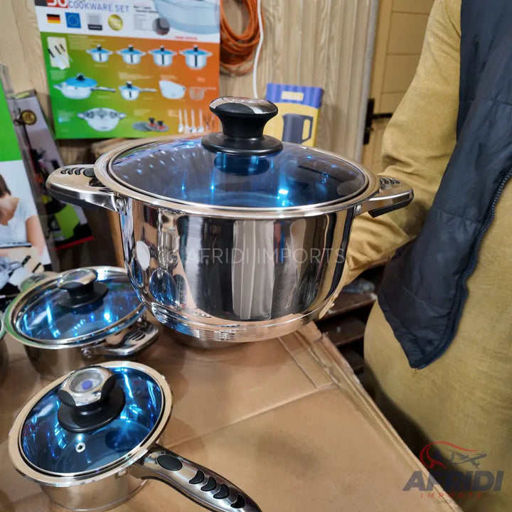 Stainless steel cookware set with blue-tinted glass lids.