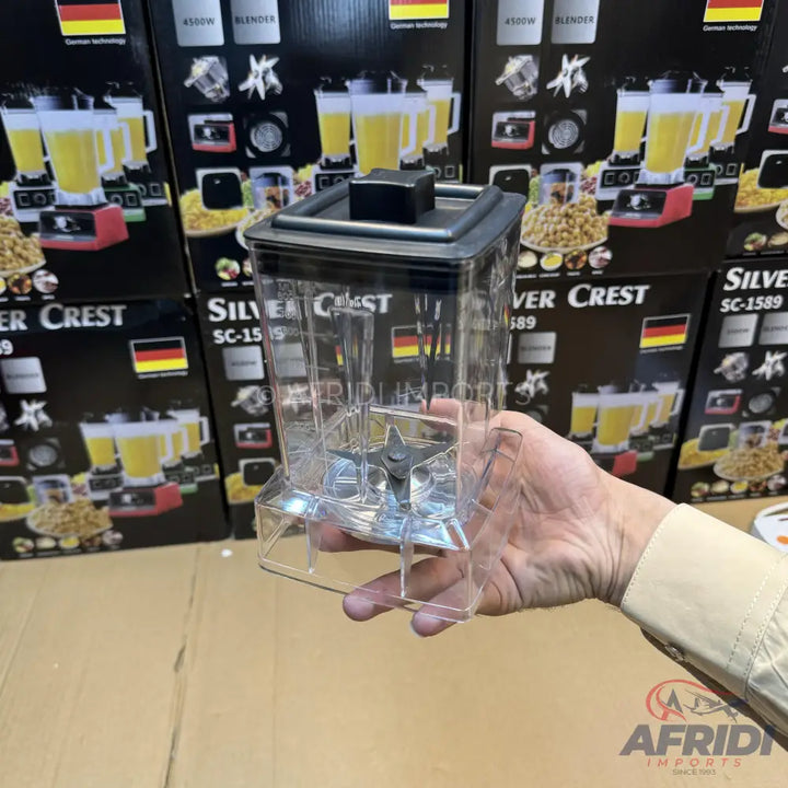 A clear plastic blender jar with a black lid and a four-blade assembly at the bottom.