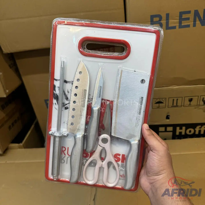A set of kitchen knives, a cleaver, a sharpener, and scissors, packaged together on a red-trimmed white board.