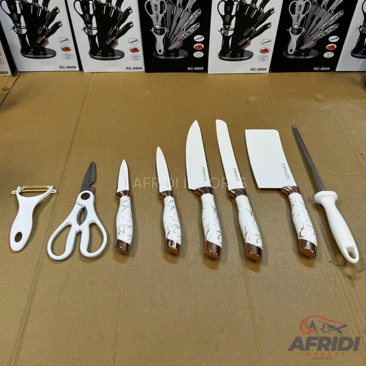 A set of kitchen knives and tools with white and rose gold handles.