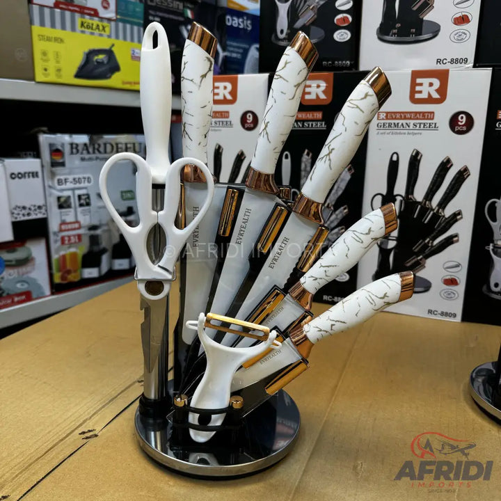 A 9-piece knife set with white marble-patterned handles and rose gold accents, including a peeler and scissors, displayed in a rotating stand.