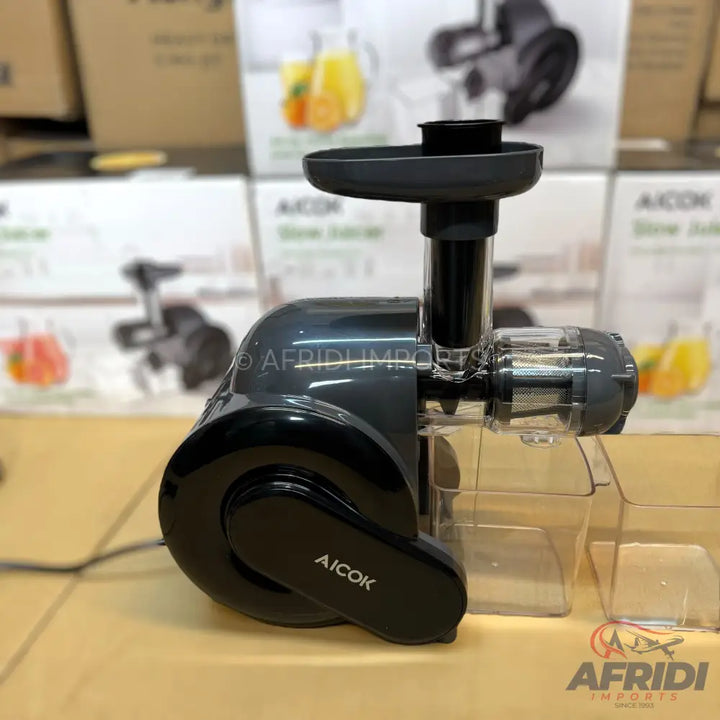 Dark gray and black masticating juicer with a transparent auger and pulp/juice containers.