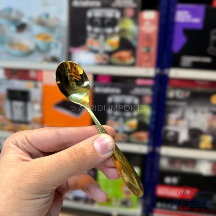 Shiny gold-colored spoon held in a hand.