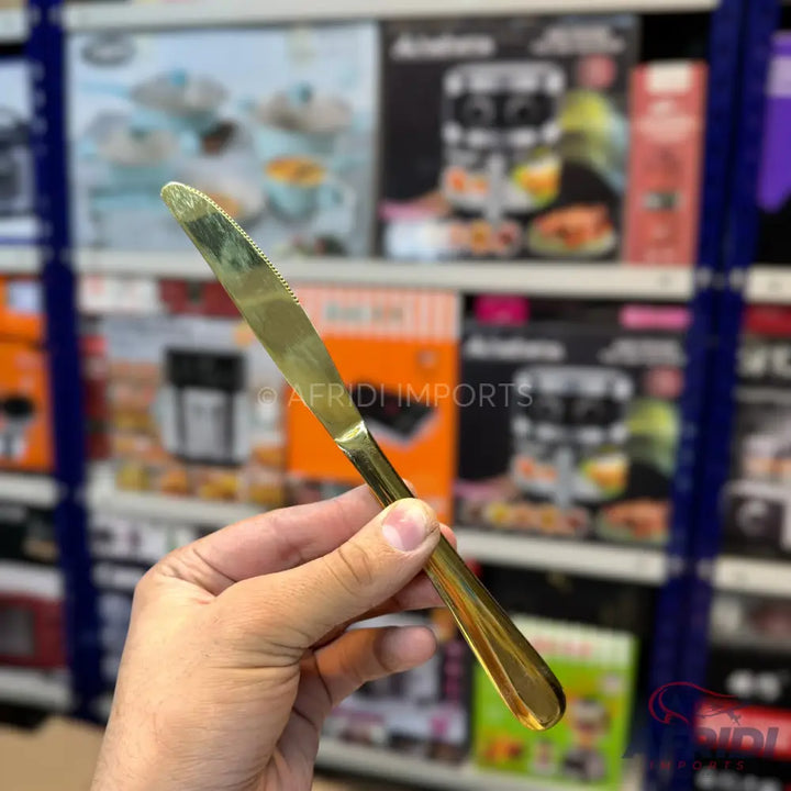 A golden butter knife with a serrated edge.