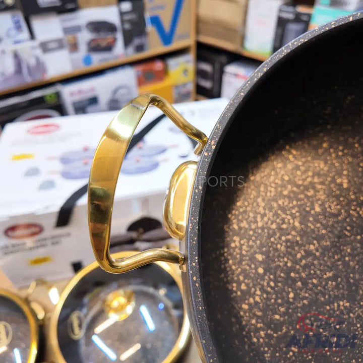 A black cooking pot with a speckled interior and gold-colored handles.