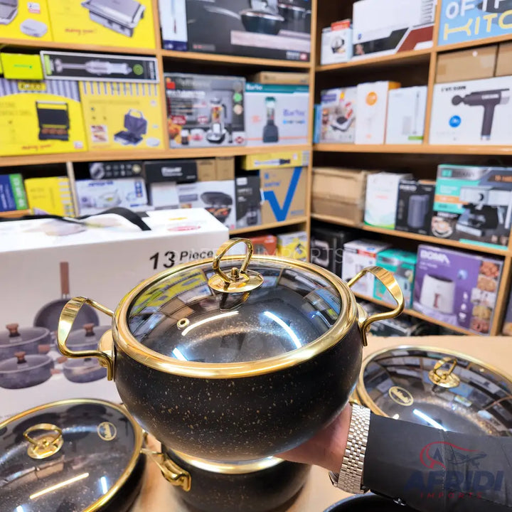 Black granite cooking pot with a gold rim and handles, and a glass lid.