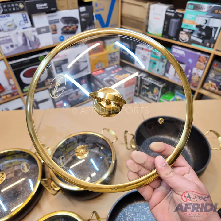 A gold-rimmed glass pot lid with a matching gold knob handle.