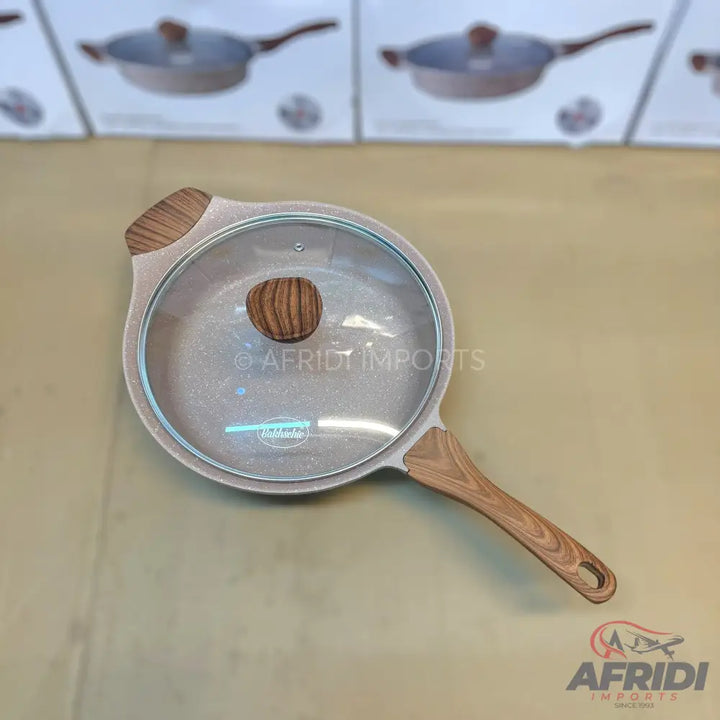 Light-colored non-stick frying pan with a glass lid and wood-patterned handles.