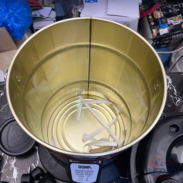 An empty gold-colored metal drum of a vacuum cleaner with some paper scraps inside.