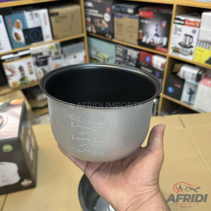 A gray metal rice cooker pot with a non-stick black interior coating and measurement markings.