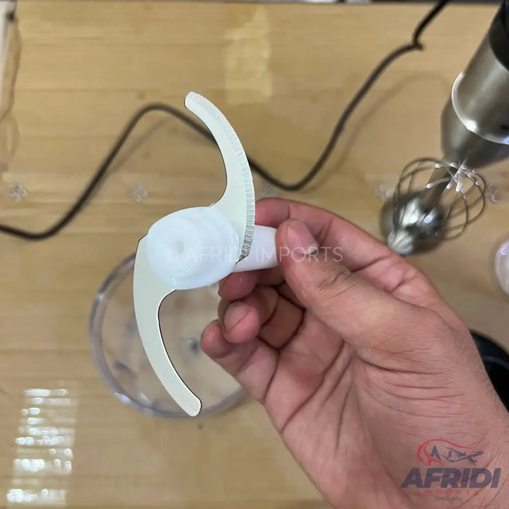 A white, two-bladed food processor attachment with serrated edges.