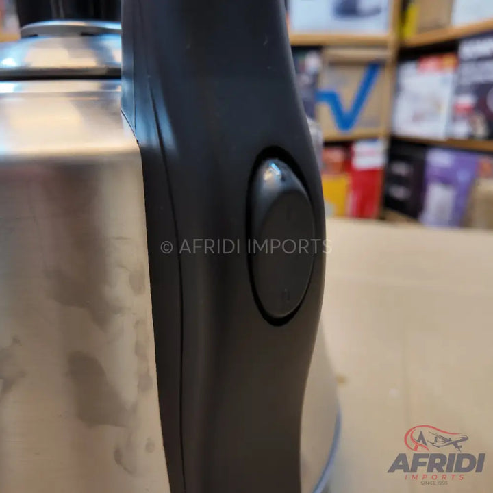 Stainless steel electric kettle with a black handle and power switch.