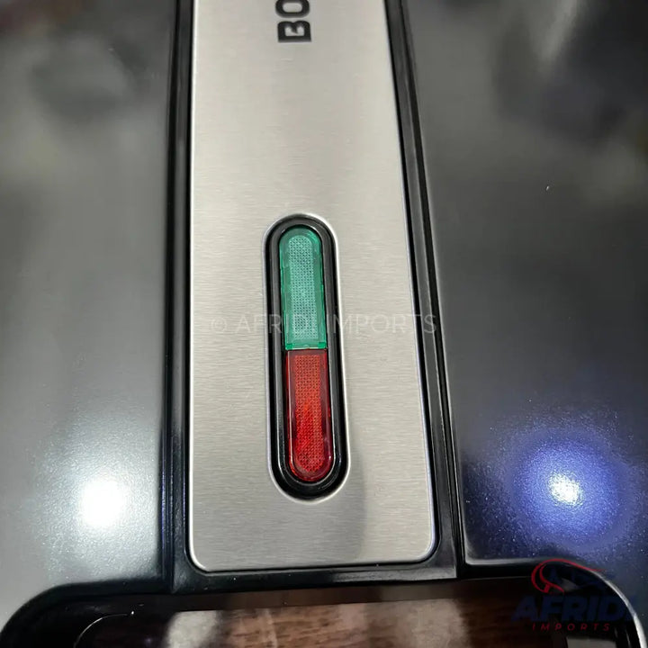 A kitchen appliance with a brushed metal top panel, featuring a vertical indicator light with a green section on top and a red section on the bottom.
