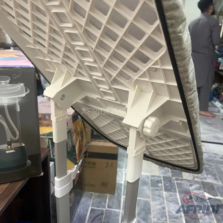 An adjustable, foldable ironing board with a grid-patterned underside.