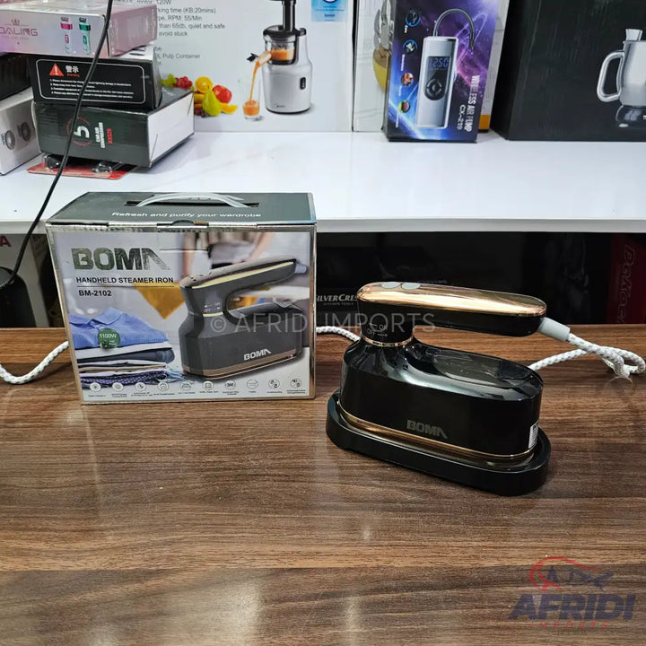 A black and gold handheld steamer iron, packaged in a box, for sale.