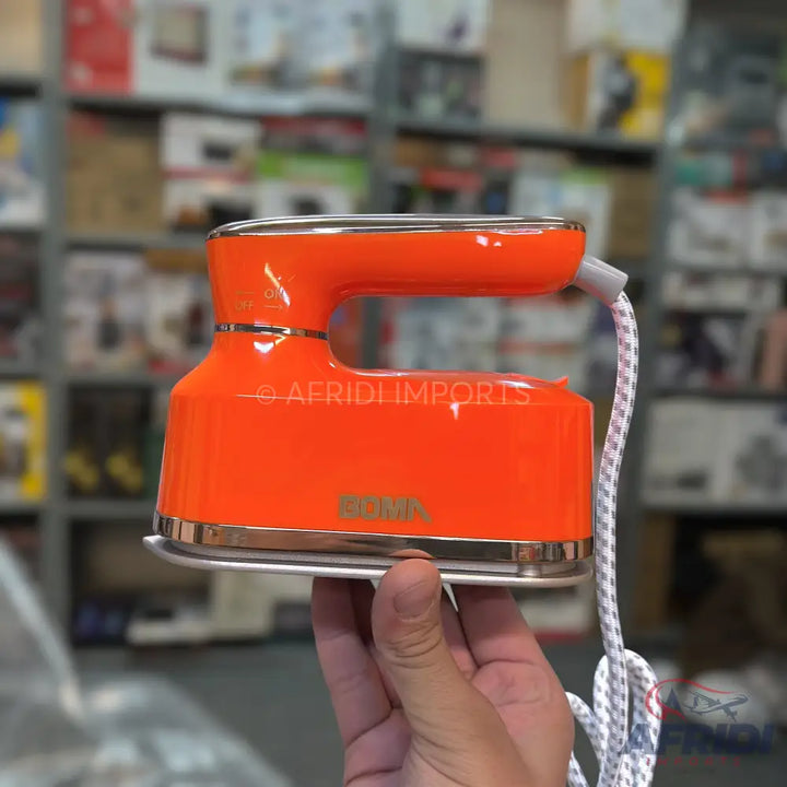 Orange travel-sized electric iron with a silver soleplate.