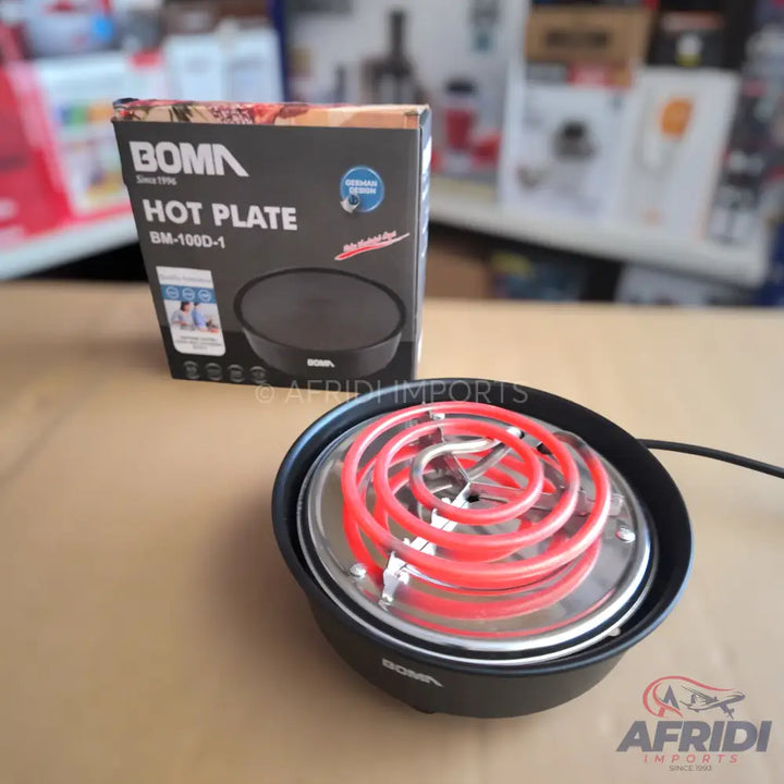 A black electric hot plate with a visible red heating coil, accompanied by its packaging box.