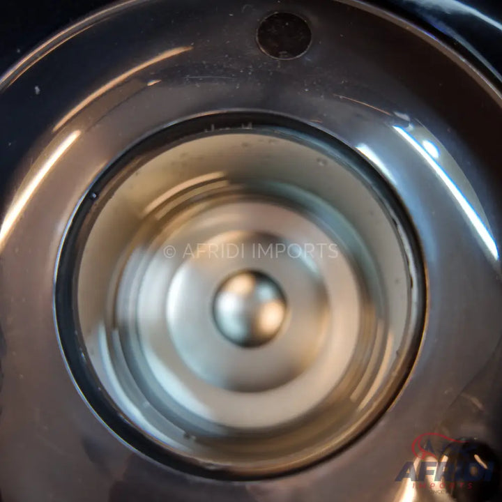 A shiny, metallic, circular disc or cap, possibly part of a mechanical device, with a central raised dome.