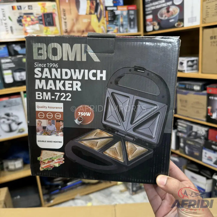 A black Boma sandwich maker (model BM-722) with 750W power and a non-stick cooking surface, designed to make two triangular sandwiches.