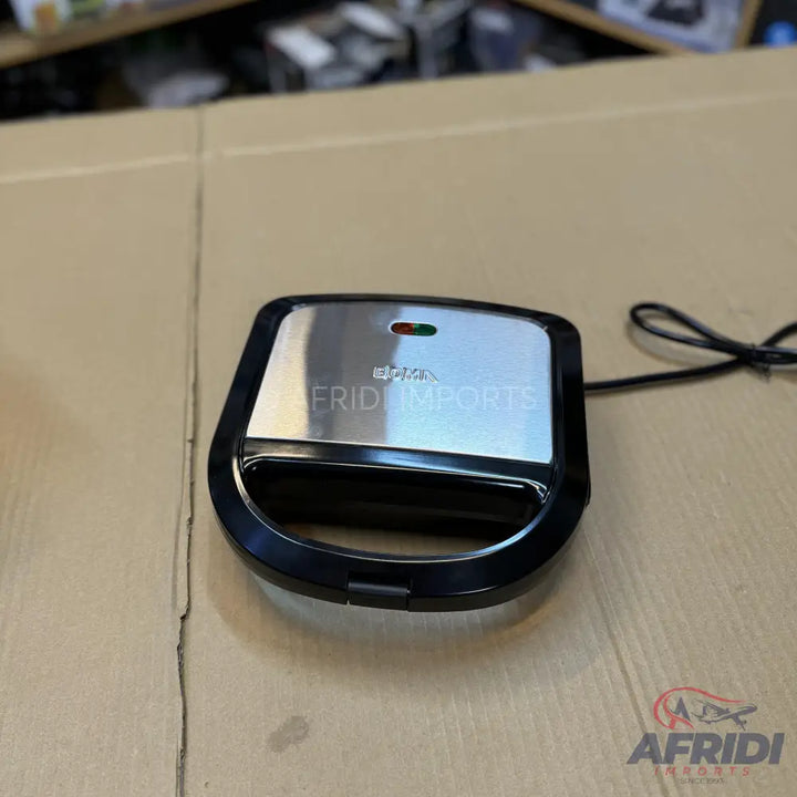 A compact, black and silver electric sandwich maker with indicator lights.
