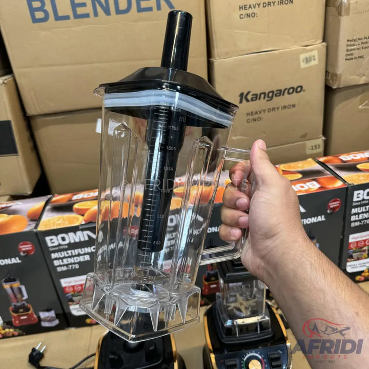 A clear plastic blender pitcher with a black lid and plunger, featuring measurement markings on the side.