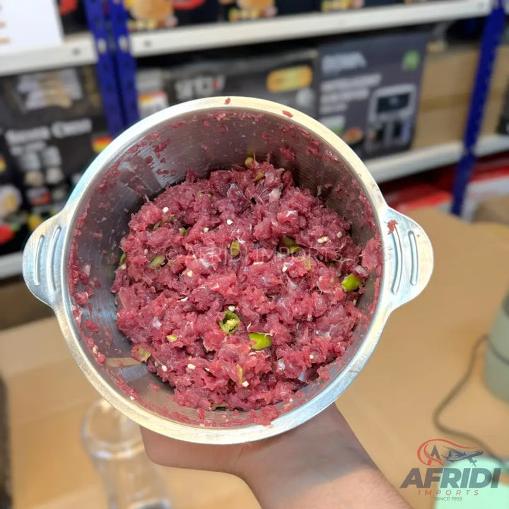 Finely ground raw meat with visible pieces of green chili and white specks, likely fat or onion, in a metal bowl.