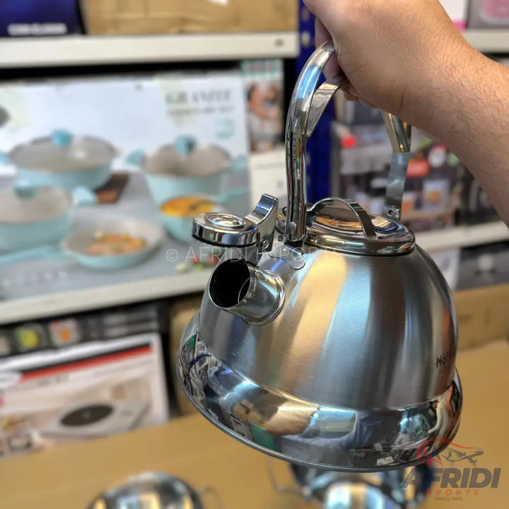 Shiny stainless steel whistling tea kettle with a black handle.