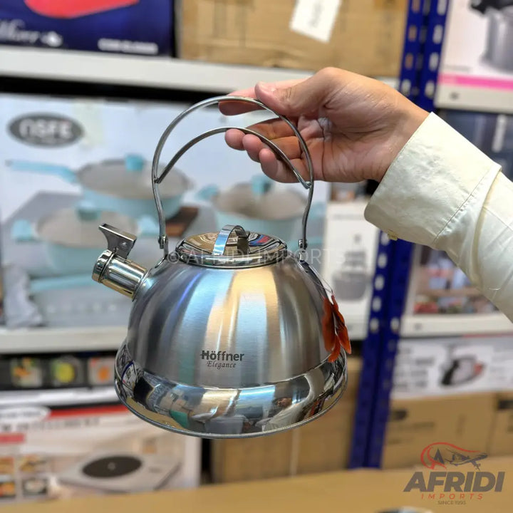Shiny stainless steel whistling tea kettle with a curved handle.