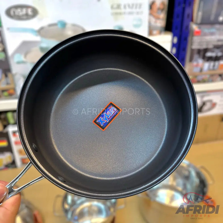 A dark-colored, non-stick cooking pot with a foldable handle, ideal for camping or outdoor use.