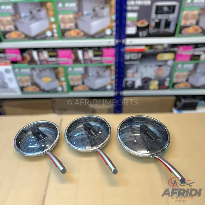 Set of three round stainless steel frying pans with lids and red-accented handles.