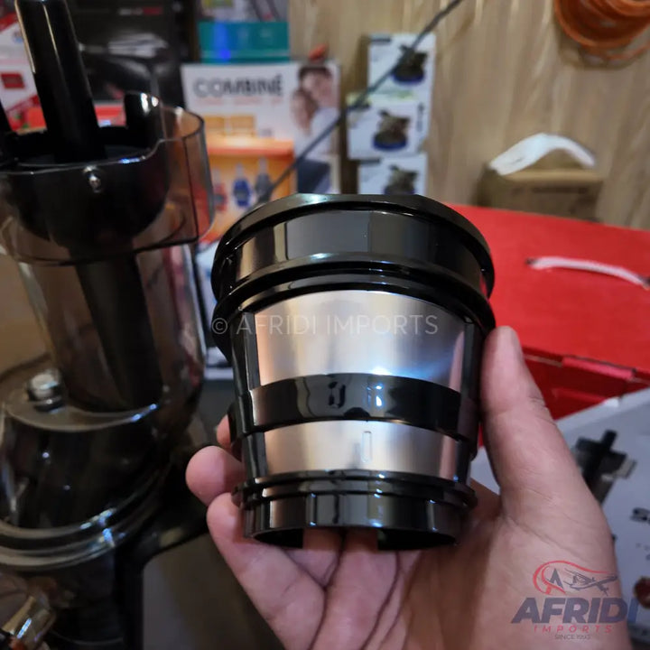 A black and silver juicer filter being held in a hand.