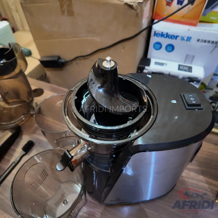 Black and silver slow juicer with an auger visible.