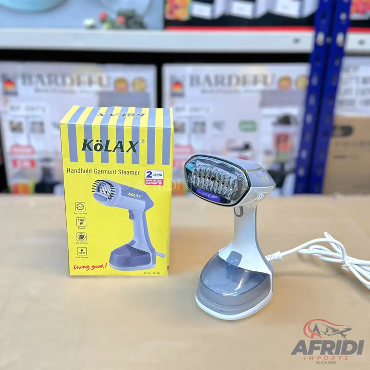 A white and grey handheld garment steamer with a clear water tank, accompanied by its yellow and blue striped box.