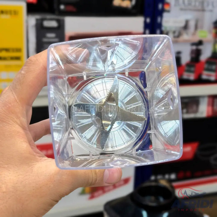 A clear plastic blender jar with a four-pronged metal blade assembly.