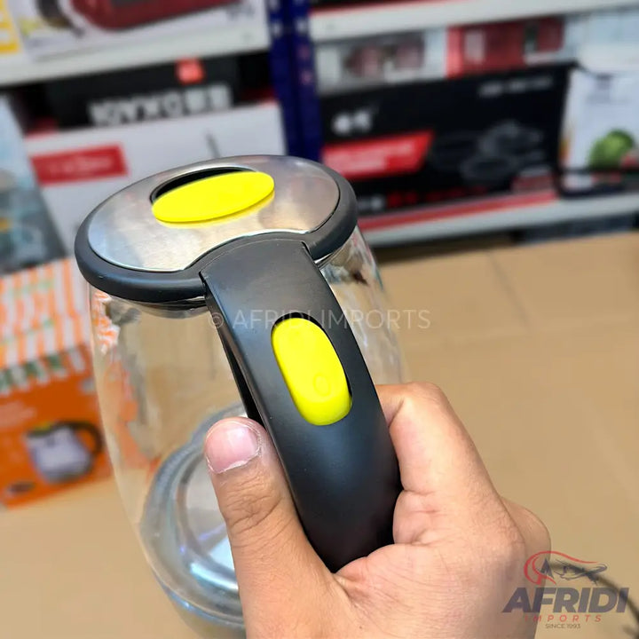 Clear glass electric kettle with a black handle and yellow power buttons.