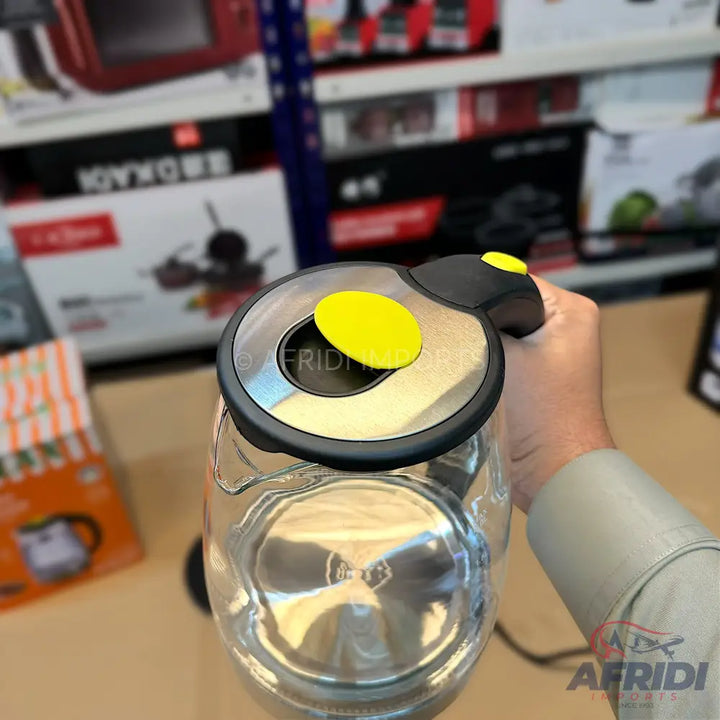 A clear glass electric kettle with a black handle and a yellow lid button.
