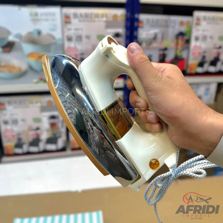 A compact, cream-colored travel iron with a gold-trimmed soleplate and a wrapped power cord.