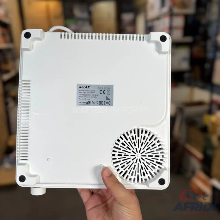 The underside of a white portable induction cooktop with a visible fan vent and product label.