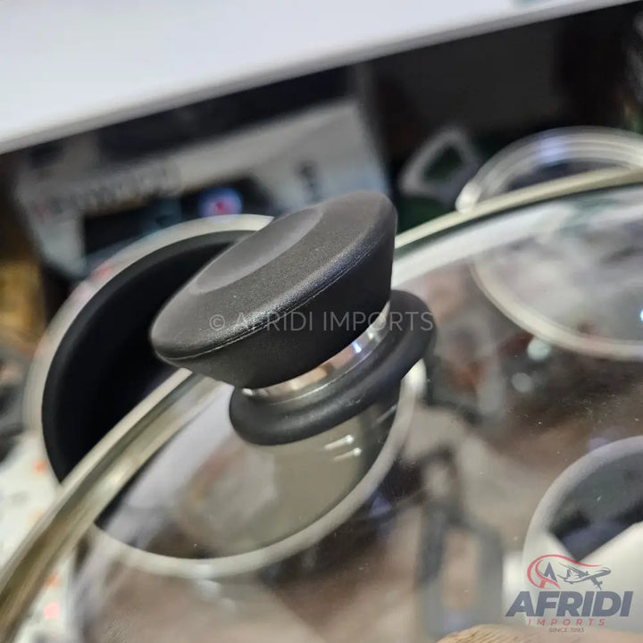 Glass pot lid with a black handle.