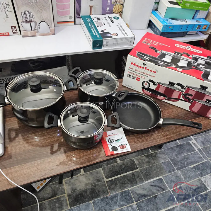 Set of stainless steel pots and a frying pan with glass lids and black handles.