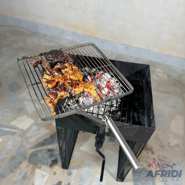 A black portable grill with a rotating grate and a crank handle, cooking chicken and other meats over hot coals.