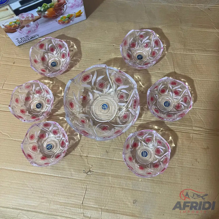 A set of seven clear glass serving bowls with a red and white floral design.
