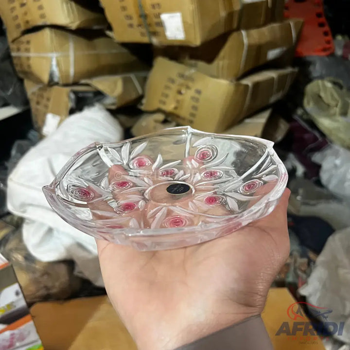 Clear glass dish with a central black accent and pink floral-like patterns.